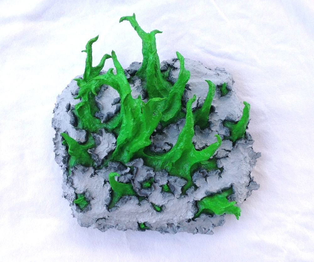 Full view of an original sculpture by MJ Seal made from paper mache that resembles spiky, spring green tentacles breaking out of a gray, papery skin