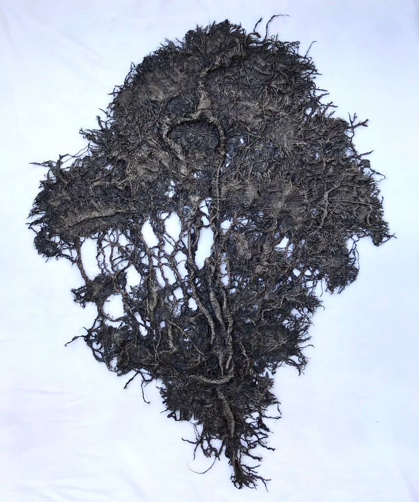Full view of an abstract fabric sculpture by MJ Seal that resembles a giant, dark gray sea fan
