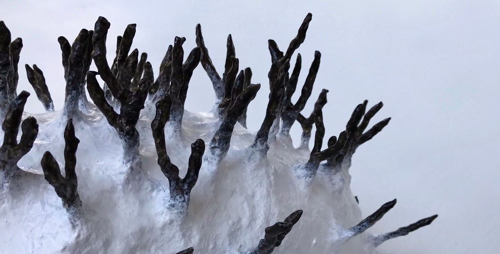 Detail of an abstract paper mache sculpture by MJ Seal that resembles a primitive white sea creature with black spikes poking out