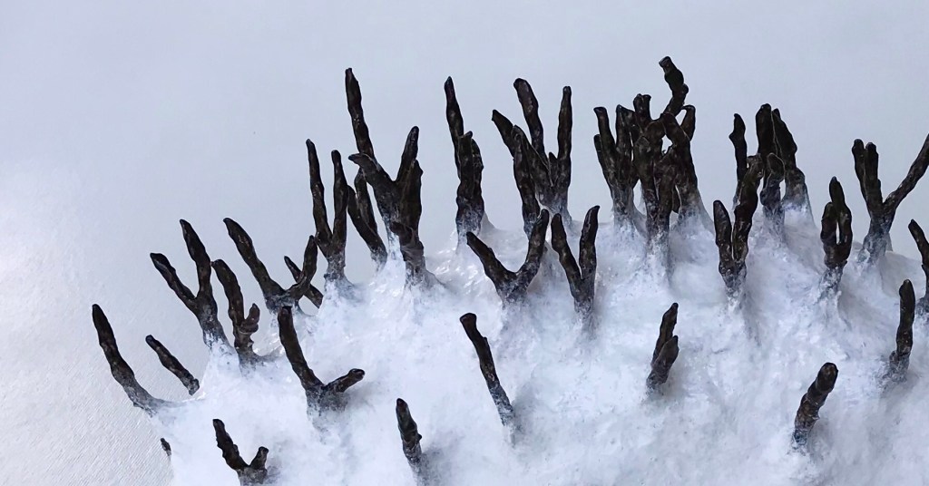 Detail of an abstract paper mache sculpture by MJ Seal that resembles a primitive white sea creature with black spikes poking out