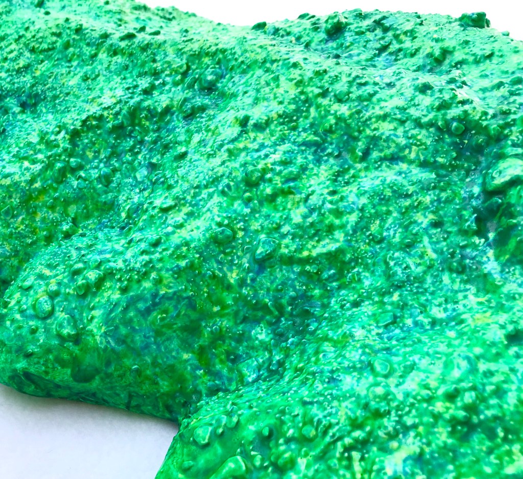 Detail of an abstract paper mache by MJ Seal that resembles a cross between a mountain and a primitive sea creature with green reptilian skin