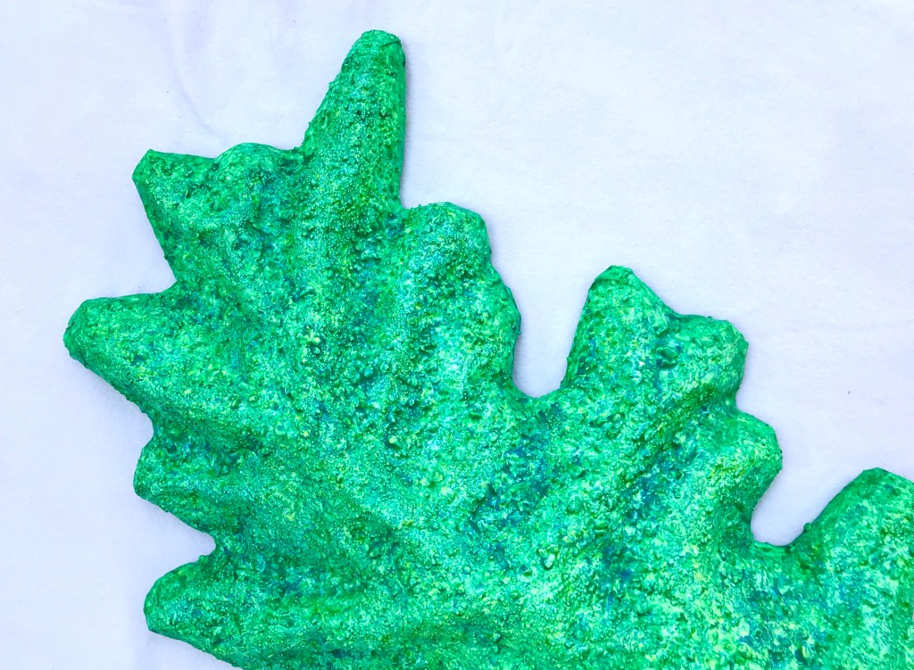 Detail of an abstract paper mache by MJ Seal that resembles a cross between a mountain and a primitive sea creature with green reptilian skin