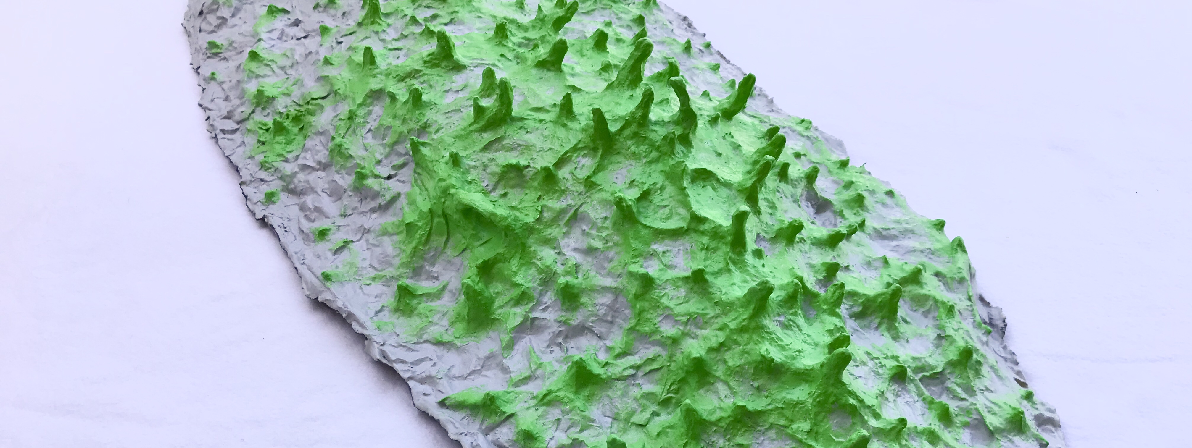 Close up detail of one of the five pieces of an abstract paper mache sculpture by MJ Seal that resmbles a group of giant gray slugs with acid green spikes roving across the ground